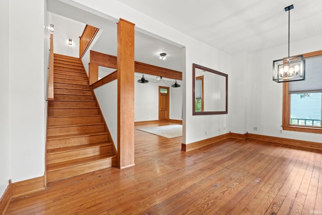 interior space featuring a notable chandelier, stairway, baseboards, and hardwood / wood-style flooring