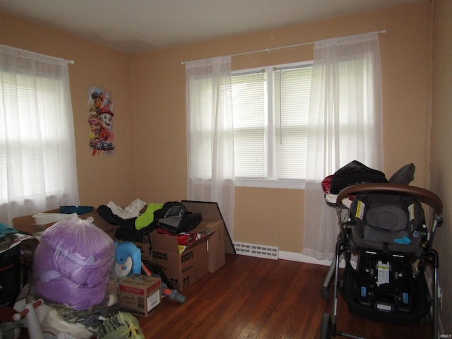 bedroom with multiple windows and dark hardwood / wood-style floors