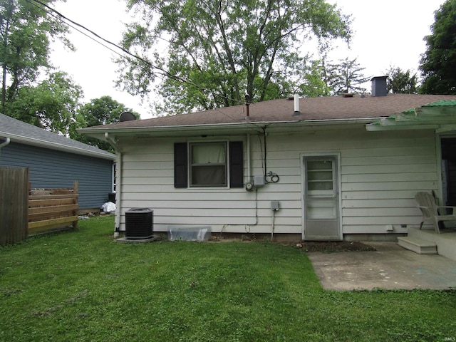 rear view of house with central air condition unit and a yard