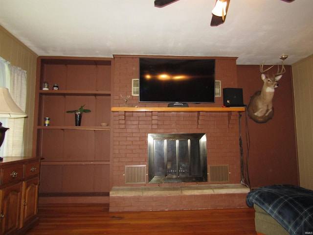 living room featuring brick wall, a fireplace, hardwood / wood-style flooring, and ceiling fan