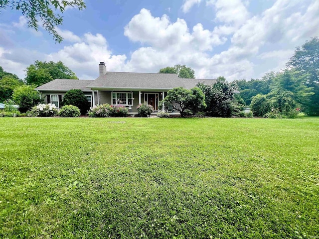 view of front facade with covered porch, a chimney, and a front lawn