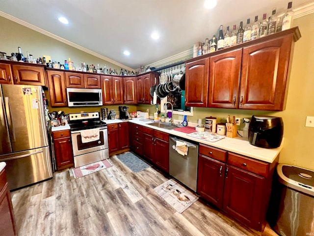 kitchen with light hardwood / wood-style flooring, stainless steel appliances, sink, crown molding, and lofted ceiling