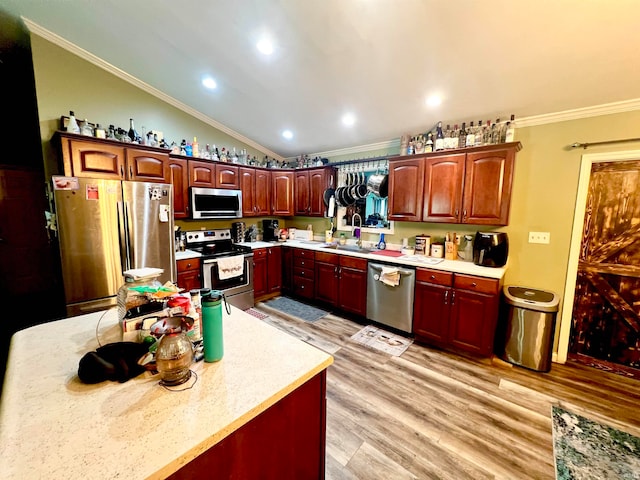 kitchen featuring light hardwood / wood-style floors, appliances with stainless steel finishes, vaulted ceiling, sink, and ornamental molding