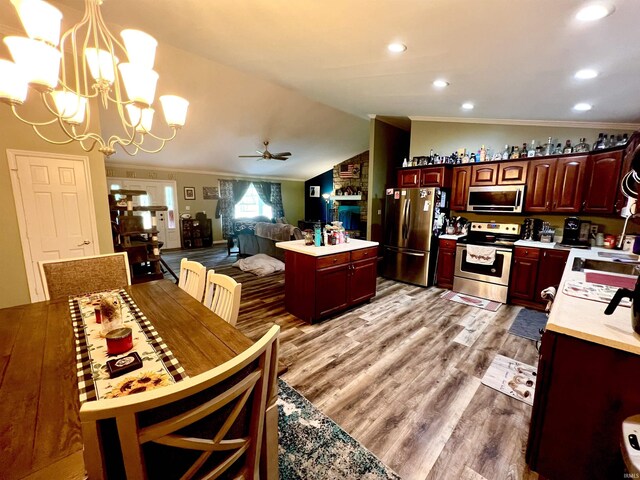 kitchen with a kitchen island, stainless steel appliances, light wood-style floors, light countertops, and lofted ceiling