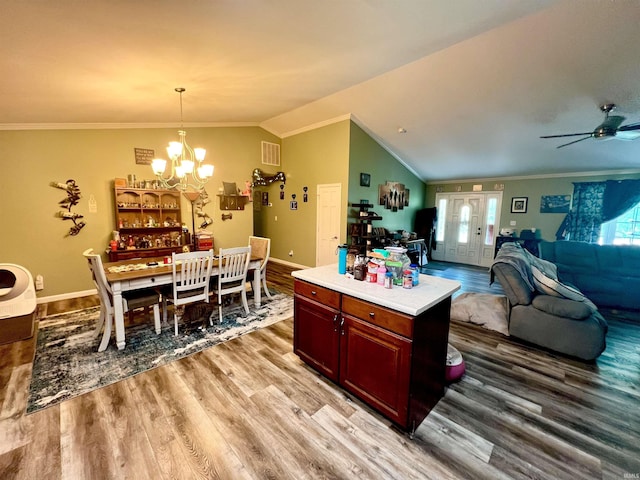 kitchen featuring light wood-style flooring, light countertops, ornamental molding, and vaulted ceiling