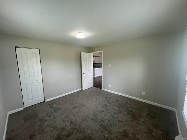 unfurnished bedroom featuring baseboards and dark carpet