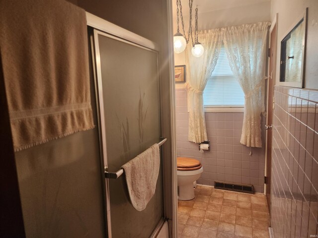 bathroom featuring toilet and tile walls