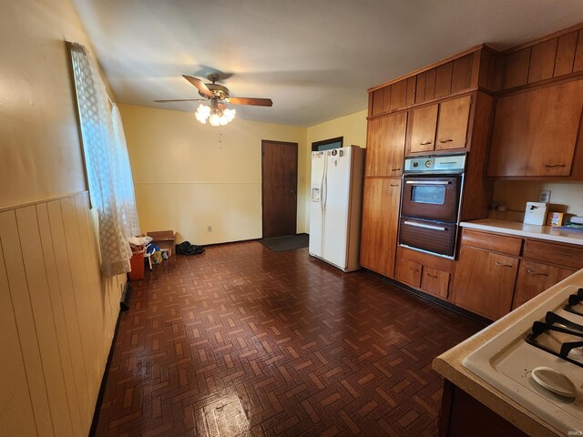 kitchen featuring wall oven, white fridge with ice dispenser, ceiling fan, and wood walls