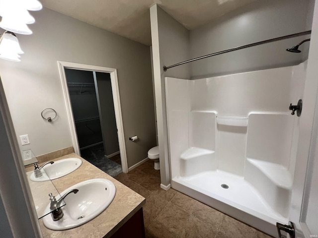 bathroom with tile patterned floors, vanity, toilet, and a shower