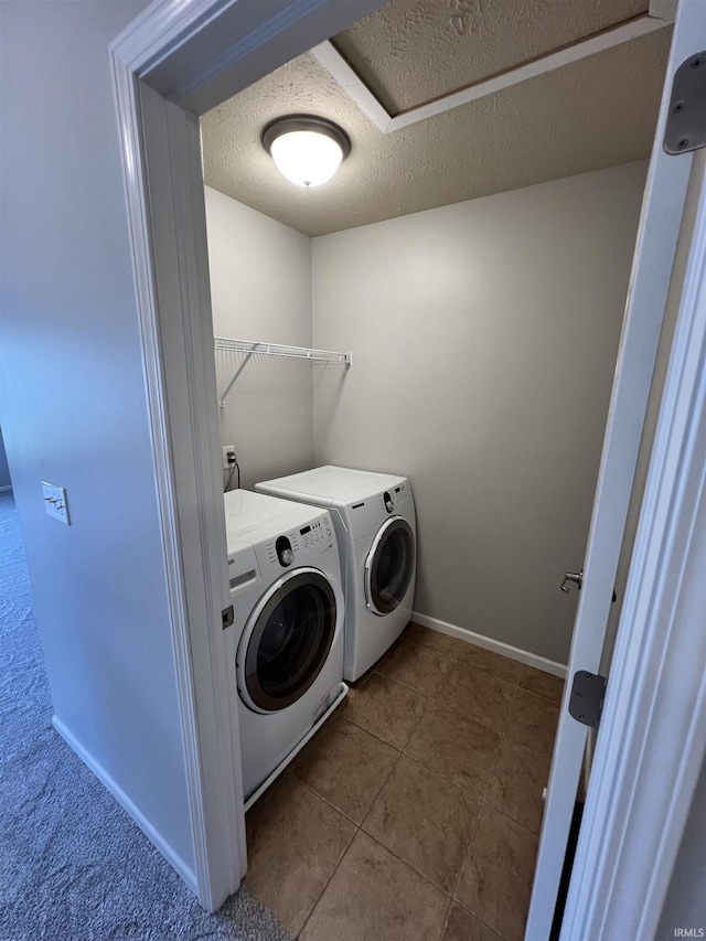 washroom with light tile patterned floors, washer and dryer, and a textured ceiling