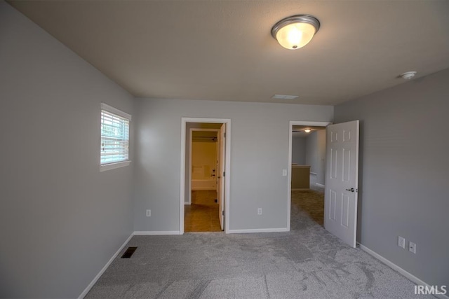 unfurnished bedroom featuring connected bathroom and light carpet