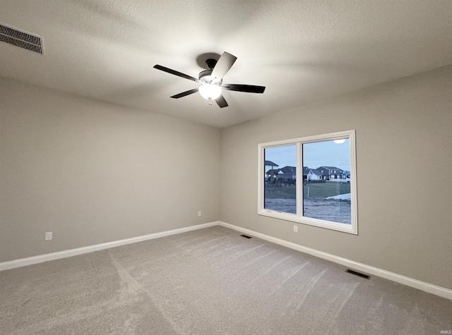 empty room with carpet, ceiling fan, and a textured ceiling