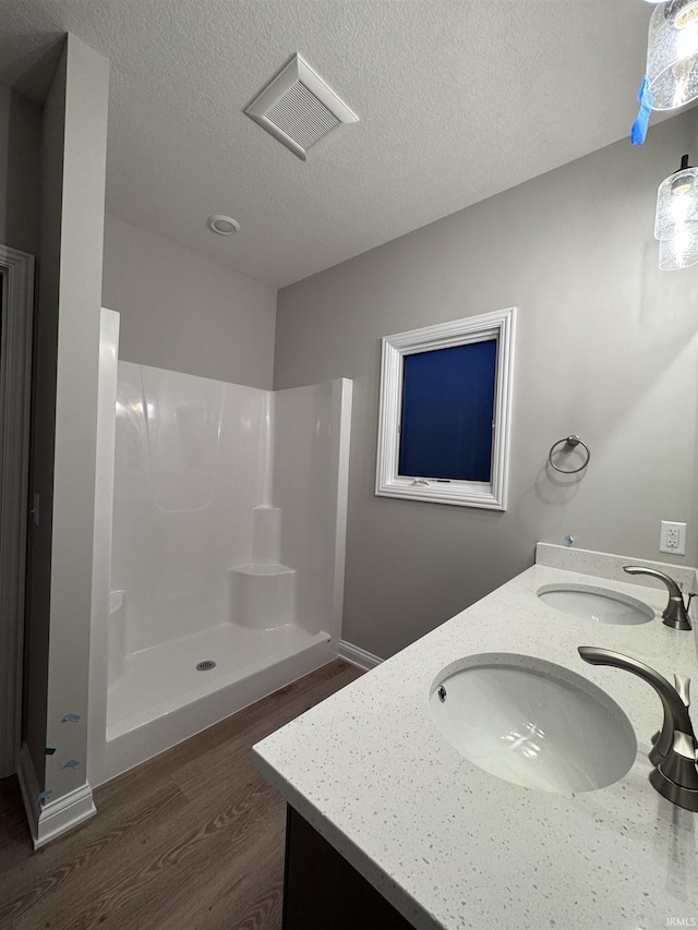 bathroom featuring hardwood / wood-style flooring, vanity, a shower, and a textured ceiling