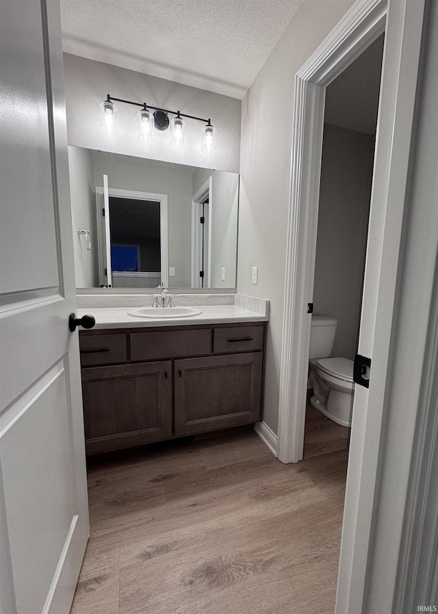 bathroom featuring hardwood / wood-style floors, vanity, toilet, and a textured ceiling