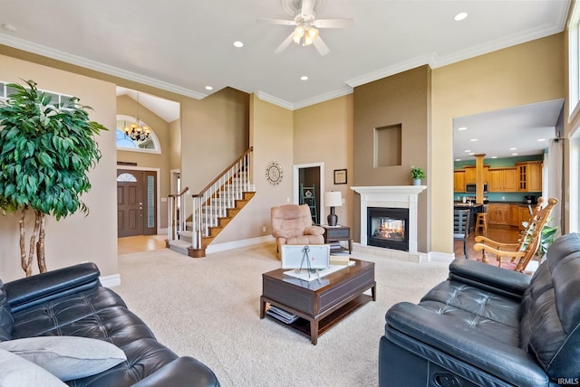 carpeted living room featuring a tile fireplace, ceiling fan with notable chandelier, and ornamental molding