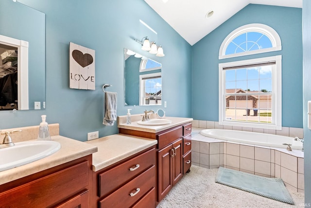 bathroom with a relaxing tiled tub, dual bowl vanity, and vaulted ceiling