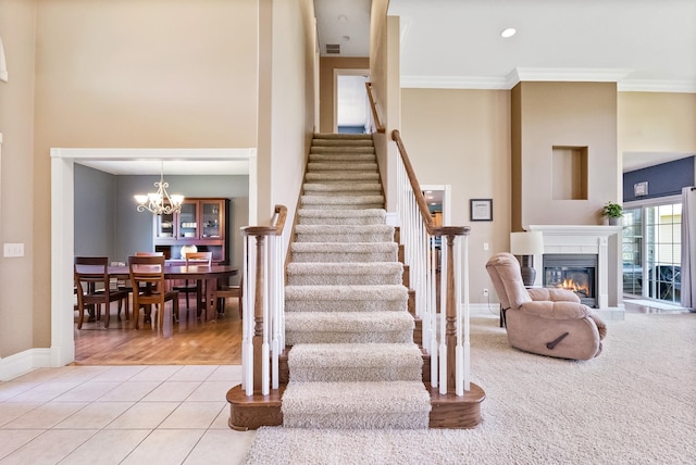 staircase featuring a notable chandelier, light tile patterned flooring, and ornamental molding