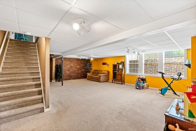 game room with carpet flooring, a drop ceiling, and brick wall