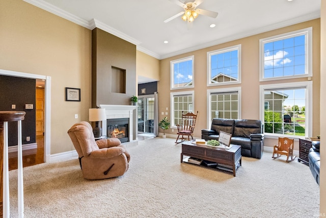 carpeted living room featuring a high ceiling, crown molding, and ceiling fan