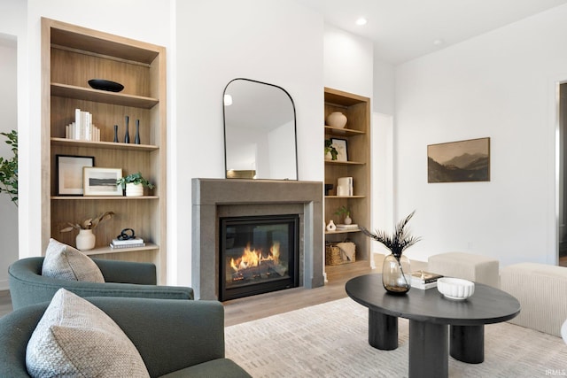 living room featuring built in shelves and light hardwood / wood-style flooring