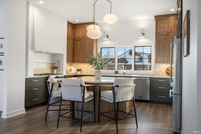 kitchen featuring stainless steel appliances, a center island, dark hardwood / wood-style flooring, and decorative light fixtures