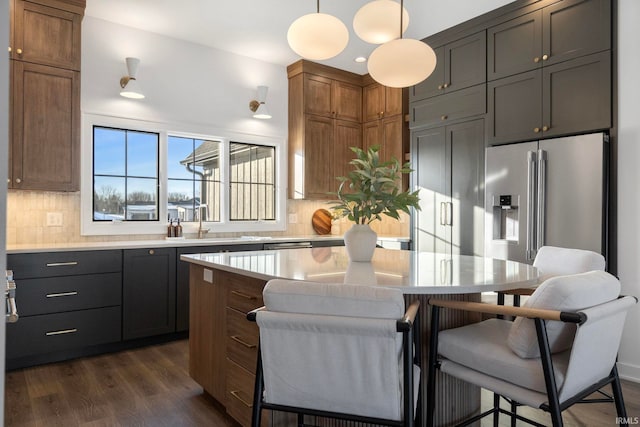 kitchen featuring tasteful backsplash, high end fridge, sink, and decorative light fixtures