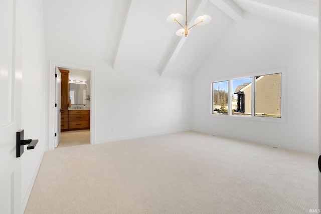 unfurnished bedroom with ensuite bath, an inviting chandelier, beam ceiling, high vaulted ceiling, and light carpet