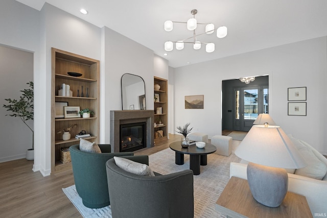 living room with hardwood / wood-style floors, an inviting chandelier, and built in shelves