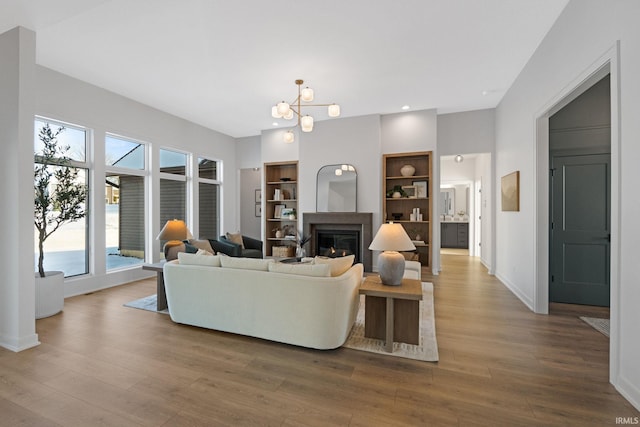 living room featuring hardwood / wood-style flooring, built in features, and a notable chandelier