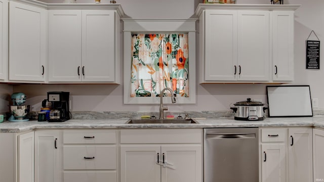 kitchen with light stone counters, stainless steel dishwasher, sink, and white cabinetry