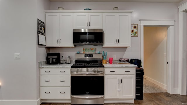 kitchen featuring light stone countertops, white cabinets, appliances with stainless steel finishes, and dark hardwood / wood-style floors