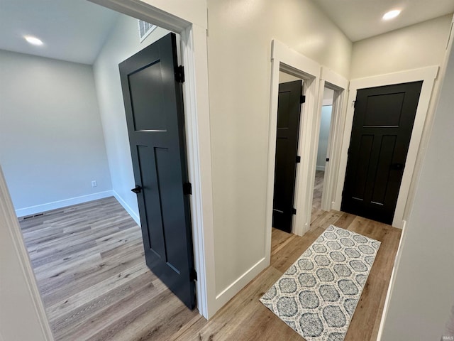 hall featuring lofted ceiling and light hardwood / wood-style floors