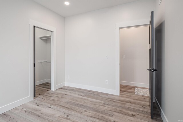 unfurnished bedroom with light wood-type flooring and a spacious closet