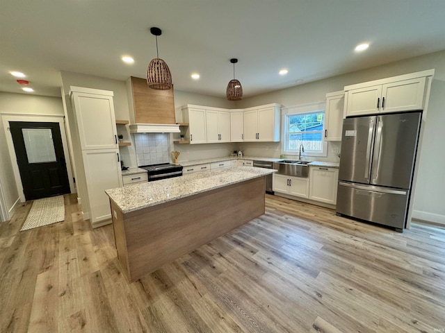 kitchen with light wood-type flooring, pendant lighting, sink, light stone countertops, and appliances with stainless steel finishes