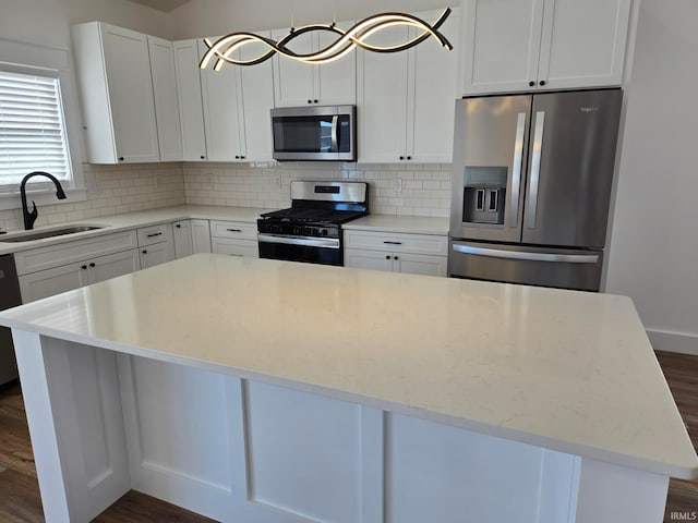 kitchen with appliances with stainless steel finishes, sink, decorative backsplash, and white cabinets