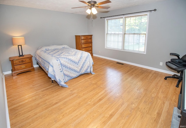 bedroom with ceiling fan, a textured ceiling, and light hardwood / wood-style flooring