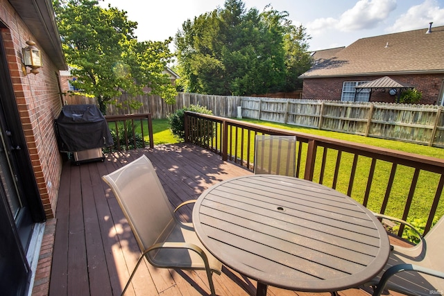 wooden deck featuring a yard and a grill