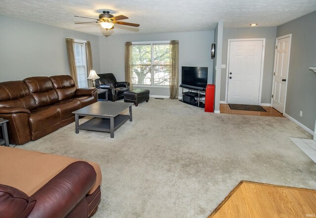 carpeted living room with ceiling fan and a textured ceiling