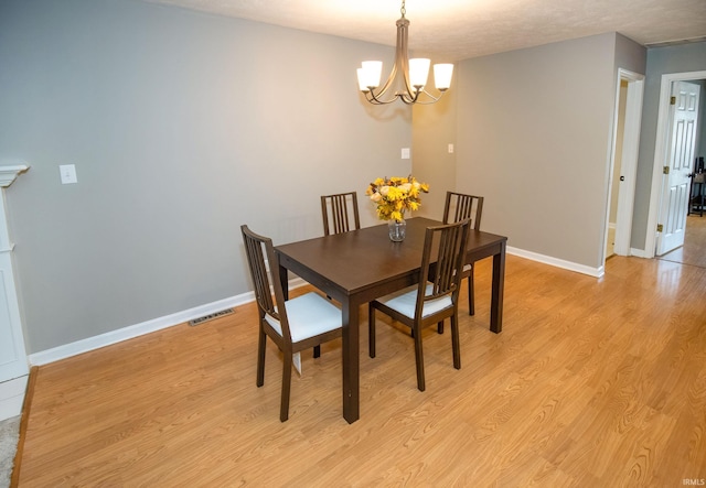 dining space featuring a textured ceiling, a notable chandelier, and light wood-type flooring