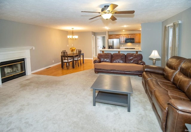 living room featuring light carpet, ceiling fan with notable chandelier, and a textured ceiling