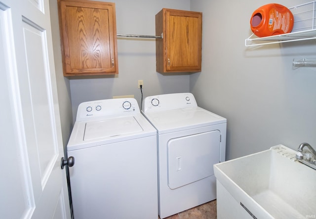 clothes washing area featuring sink, cabinets, and washing machine and clothes dryer