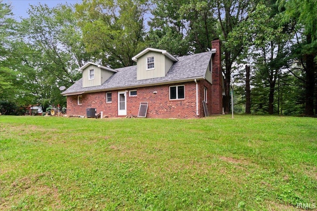 rear view of property featuring a lawn and central AC unit