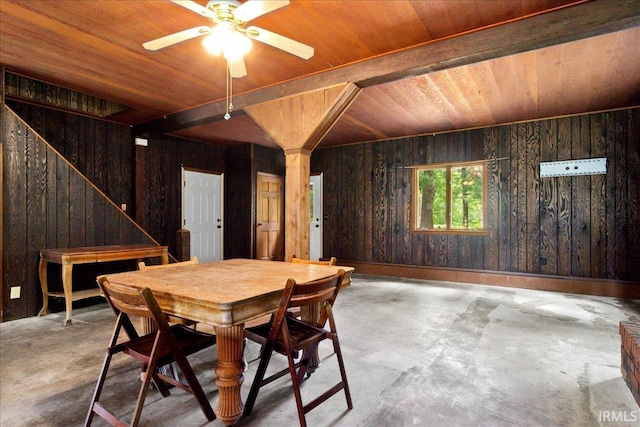 dining space featuring wood walls, wooden ceiling, ceiling fan, and concrete floors