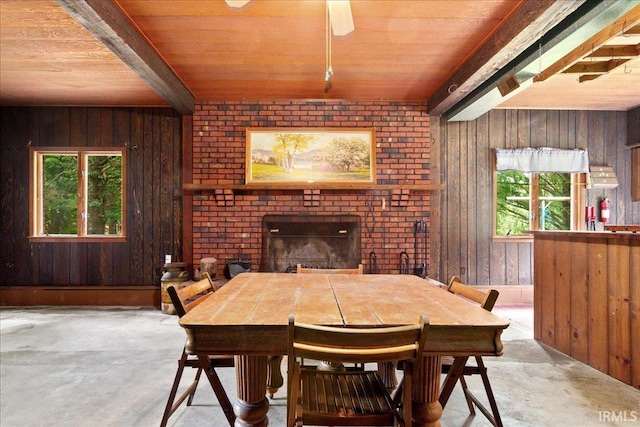 dining room featuring wood ceiling, a fireplace, concrete flooring, and wooden walls