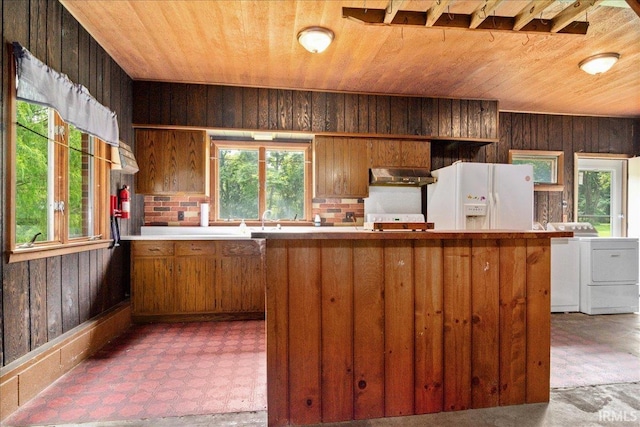 kitchen with white fridge with ice dispenser, wooden walls, exhaust hood, separate washer and dryer, and wood ceiling