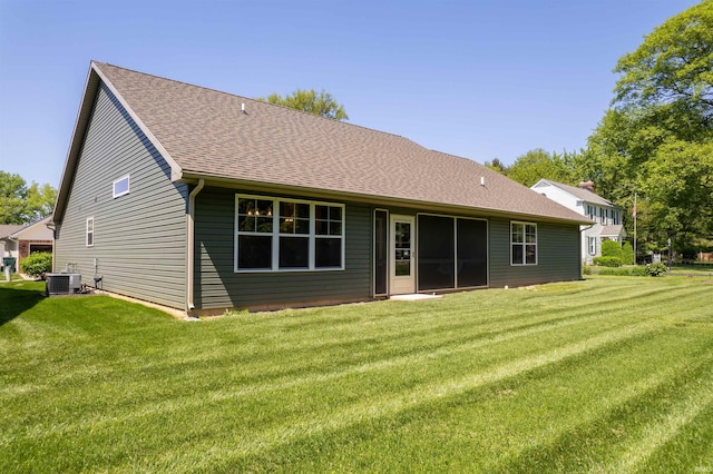 rear view of property with central AC and a lawn