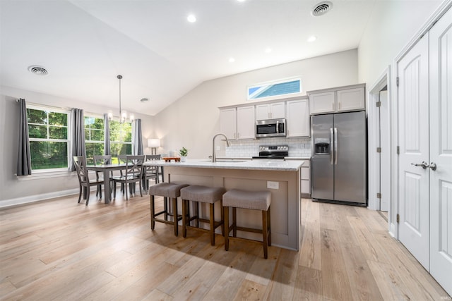 kitchen with appliances with stainless steel finishes, a breakfast bar, sink, gray cabinetry, and a center island with sink