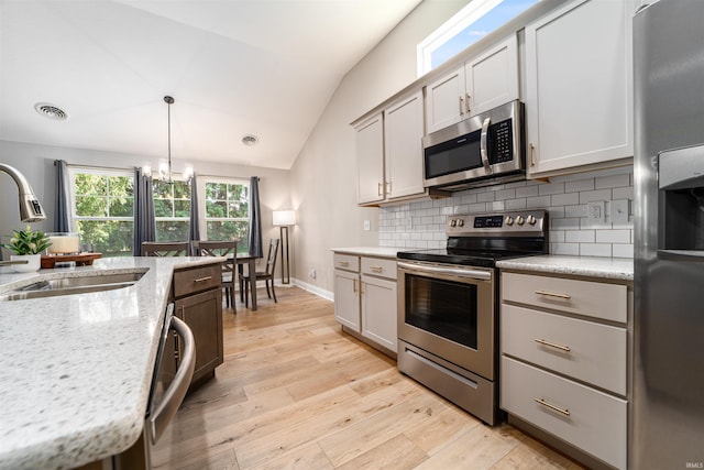 kitchen featuring sink, vaulted ceiling, hanging light fixtures, stainless steel appliances, and backsplash