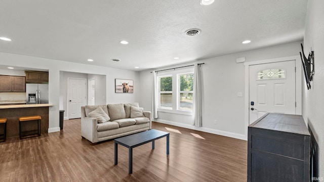 living room featuring dark wood-type flooring and a textured ceiling