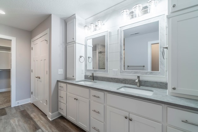 bathroom with walk in shower, hardwood / wood-style flooring, a textured ceiling, and vanity